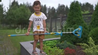 小男孩儿子用拖把拭子在花园里用玩具劈开灌木丛.家庭看<strong>重温</strong>暖的色彩夏天的场景
